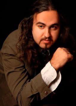 Young Mani Majd seated against a dark background